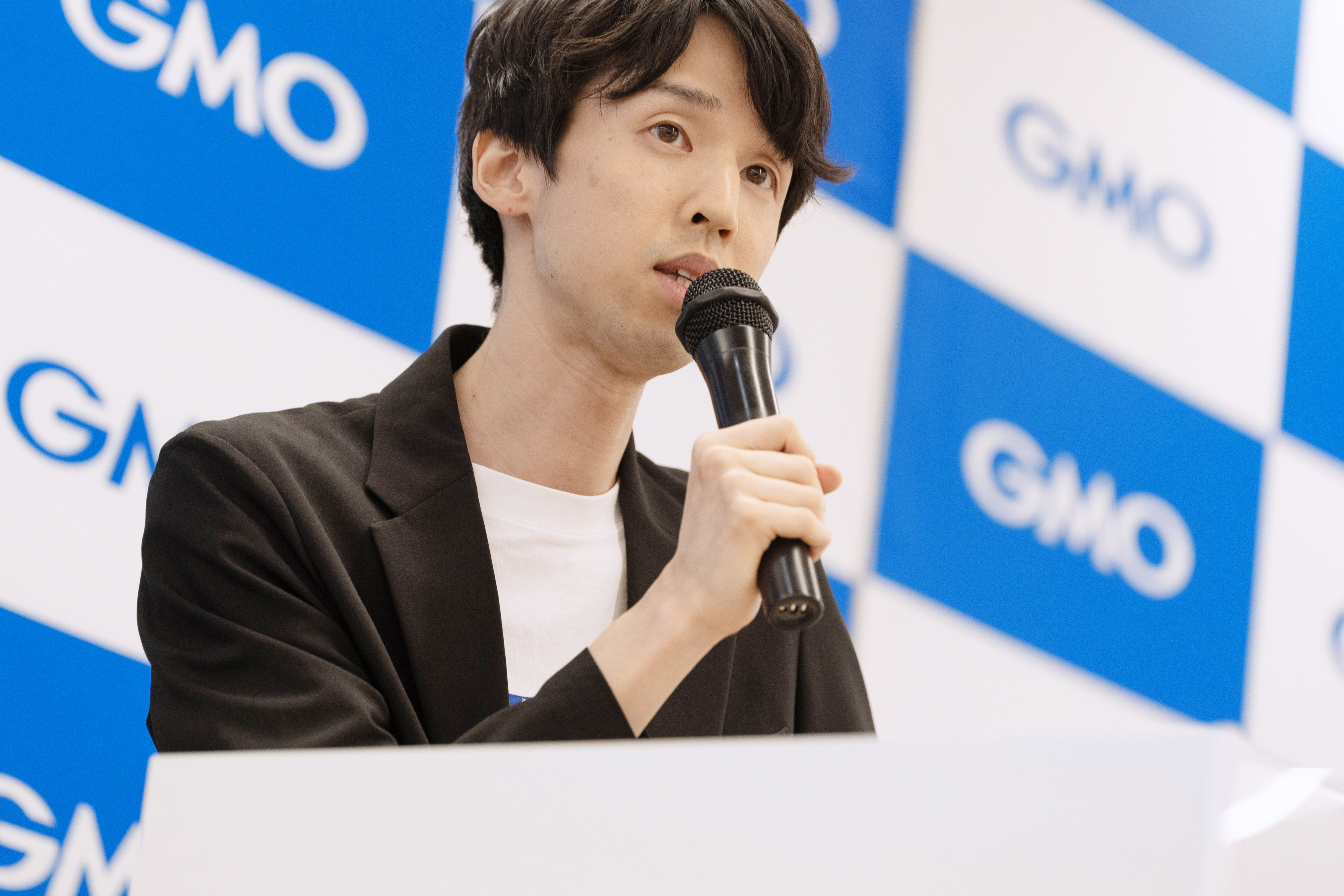 GMOの会場でマイクを持って登壇する川合卓也